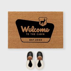 a welcome mat and pair of shoes with the words welcome to the cabin on it