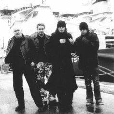 black and white photograph of four people walking in the rain on a boat dock with their arms around each other