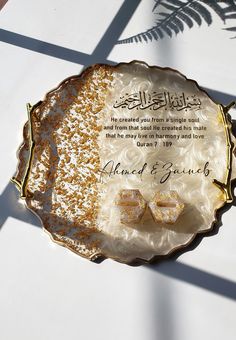 a decorative plate with two bow ties on it and an arabic quote written in the middle