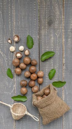 nuts and leaves on a wooden table next to a bag with some seeds in it