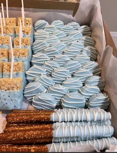 a box filled with lots of blue and white desserts next to pretzels