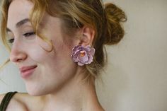 a close up of a person wearing some kind of earring with a flower on it