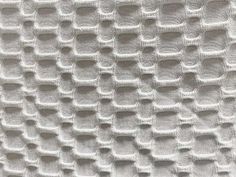 an up close shot of the texture of a white fabric with small holes in it