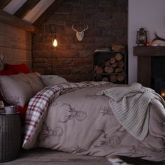 a bed in a room with brick walls and a fireplace next to it is made up