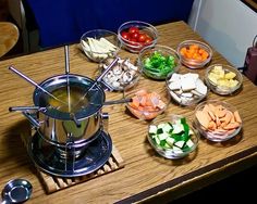 a wooden table topped with bowls filled with different types of food and utensils