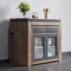 a wooden cabinet with glass doors on the top and bottom, in front of a white wall