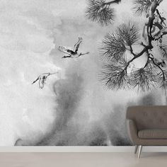 black and white photograph of birds flying in the sky above pine tree branches wall mural