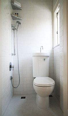 a white toilet sitting inside of a bathroom next to a shower head mounted on a wall