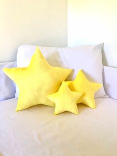 two yellow stars sitting on top of a bed next to each other in front of pillows