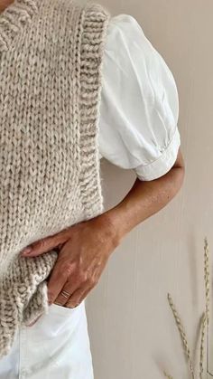 a woman is holding up a knitted sweater