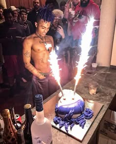 a man standing in front of a birthday cake with sparklers on it, surrounded by other people