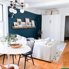 a living room filled with furniture and a white table in front of a blue wall