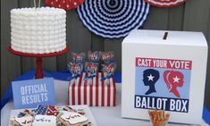 a table topped with cakes and cupcakes next to an american flag cake box