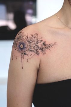 a woman with a tattoo on her shoulder has flowers in the middle of her arm