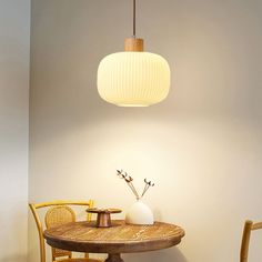 a table with two chairs and a vase on it in front of a light fixture