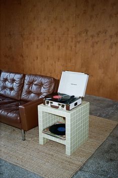 a brown leather couch sitting next to a table with a record player on top of it