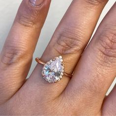 a woman's hand with a ring on it and an oval shaped diamond in the middle