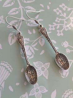 two spoons with ornate designs on them are sitting on a floral wallpapered surface