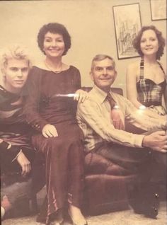 an old black and white photo of three people sitting on a couch with one woman standing next to the man