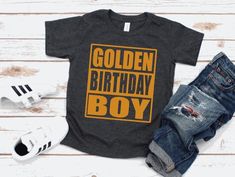 a shirt that says golden birthday boy with ripped jeans and sneakers on the floor next to it