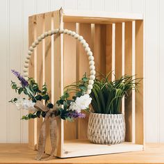 a vase filled with flowers sitting on top of a wooden shelf next to a plant