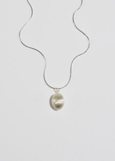 Sterling egg pendant necklace with a screw mechanism and hollow center to store a talisman. It is designed for the wearer to carry around a special, personal object to hold close to your heart — akin to a locket. Contains petite freshwater seed pearls. Each piece is hand carved, cast, and finished in New York by Owen Dunton of Dunton Ellerkamp. Available in a 16" solid snake chain or an 18" delicate oval chain. Material: Sterling silver. We recommend storing in a dry place and periodic polishing Minimalist Jewelry With Oval Locket Pendant, Minimalist Oval Pendant Keepsake Jewelry, Pearl Pendant Amulet Necklace, Sterling Silver Oval Pearl Drop Necklace, Silver Necklace With Oval Pearl Charm Pendant, Minimalist Oval Pendant Locket Necklaces, Minimalist Oval Pendant Locket Necklace, Minimalist Oval Locket Necklace, Silver Jewelry With Pearl Charm In Oval Pendant