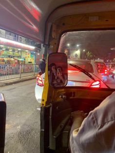 the back end of a truck with cars in it at night time and people walking down the street