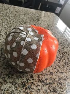 an orange sitting on top of a counter next to a black and white table cloth