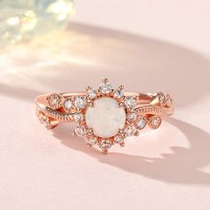 an opal and diamond ring sits on a pink surface