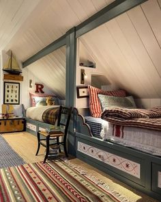 an attic bedroom with twin beds and rugs on the floor, along with other furniture