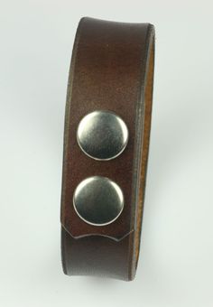 a brown leather bracelet with two metal buttons