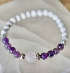 a white beaded bracelet with purple beads