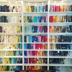 the bookshelves are filled with many different colored books and there is a bench in front of them