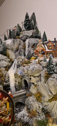 there is a model train set on display in front of the building and trees that are covered with snow