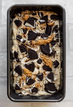 an oreo cookie ice cream dessert in a black baking pan on top of a white brick wall