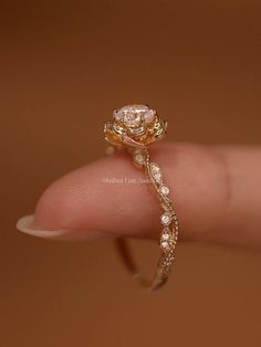 a close up of a person's hand holding a ring with a flower on it