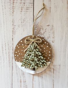 a wooden ornament with a christmas tree hanging from it's side on a white wood background