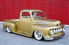 an antique pickup truck parked in front of a red wall