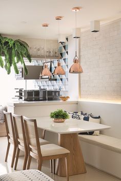 a white kitchen with wooden chairs and a plant hanging from the ceiling over the counter