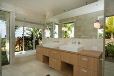 a bathroom with double sinks and large mirrors in it's center wall, along with two windows that look out onto the ocean