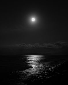 the moon is shining over the ocean at night