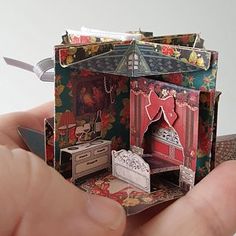 a hand holding a miniature doll house in it's left side, with the door open