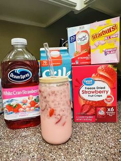 some drinks are sitting on the counter next to milk and other items that include strawberries