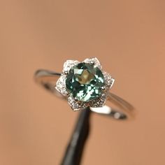 It is a lab green sapphire ring. The main stone is 7 mm*7 mm round cut).weight about 1.66 carats.The basic metal is sterling silver and plated with rhodium/14k white  gold/14k rose gold/14k yellow goldYou can also go to my shop Home for more elegant rings: https://www.etsy.com/shop/godjewelry?ref=hdr_shop_menu Customization is always welcome and please feel free to contact with me if you have any design ideas! Exquisite Green Emerald Sterling Silver Ring, Green Sapphire Ring With Halo Setting For Promise, Elegant Green Sapphire Ring With Halo Setting, Elegant Green Sapphire Ring With Center Stone, Elegant Green Sapphire Promise Ring, Elegant Green Round Cut Sapphire Ring, Green Sapphire Diamond Ring With Round Cut, Sterling Silver Emerald Ring With Brilliant Cut, Silver Sapphire Ring With Prong Setting For May Birthstone