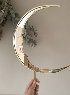 a person holding up a mirror with a crescent shaped object on it