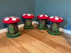 three red mushrooms sitting on top of wooden stumps in a room with blue walls