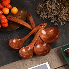 four wooden spoons on a table with tomatoes and other vegetables in bowls behind them