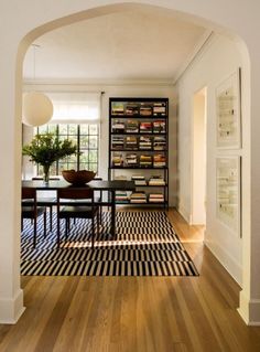 an archway leads into a dining room with black and white striped rug on the floor