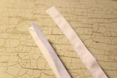 two pieces of white fabric sitting on top of a cracked floor next to each other