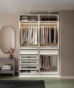 a white closet with drawers and clothes hanging on the wall next to a mirror in a room